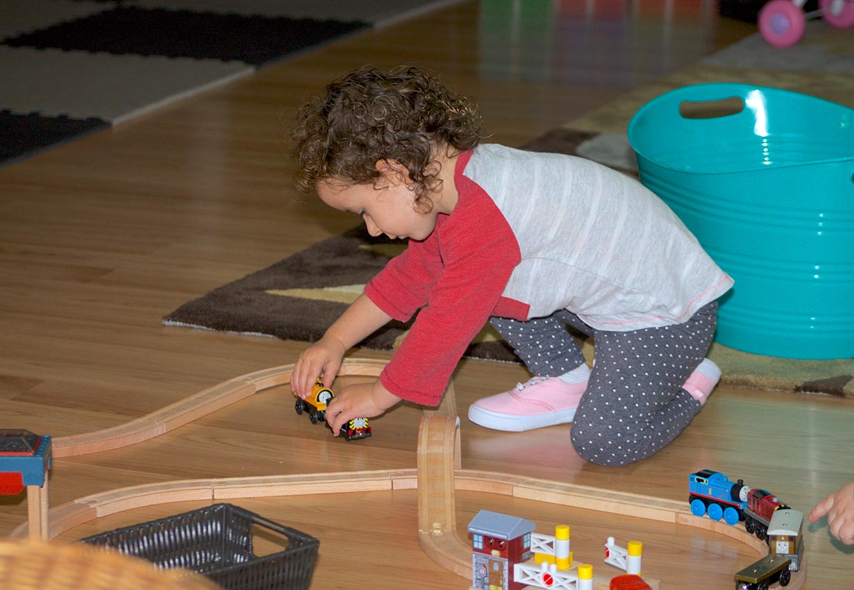 girl playing with a train set at child care